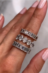 A woman has three diamond eternity rings on her finger.